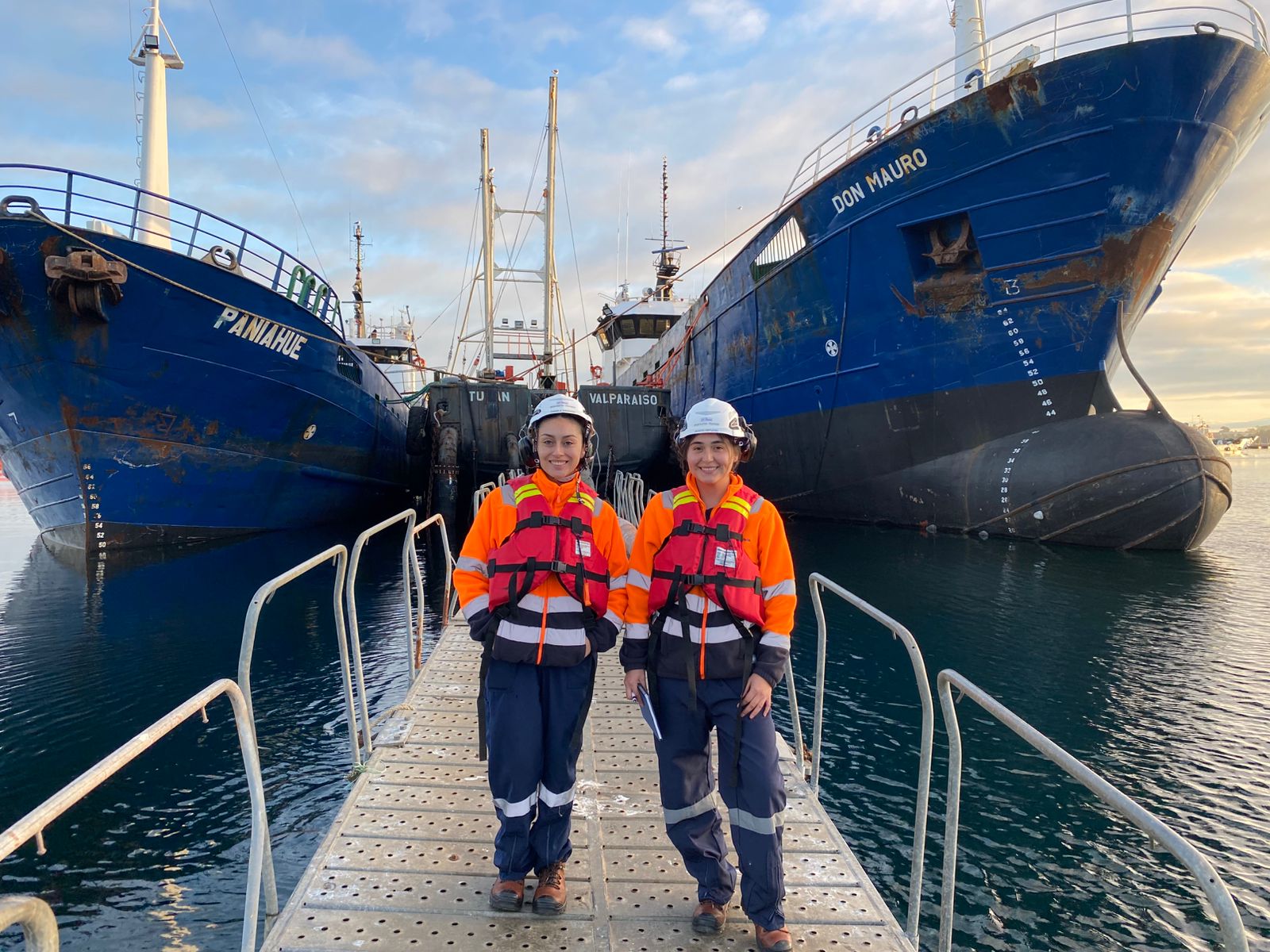 Dos profesionales de WICA con chalecos salvavidas y cascos en puerto